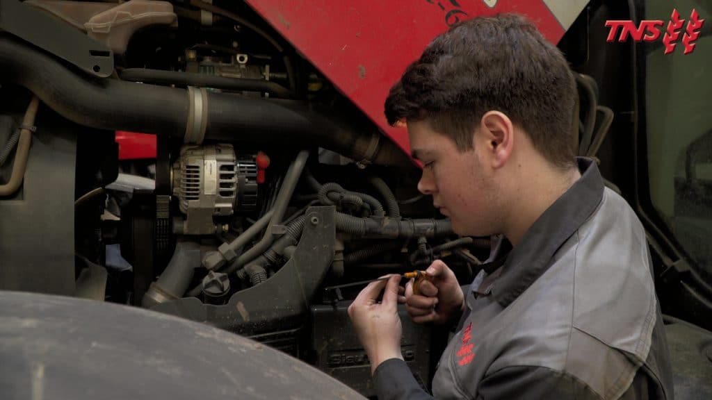 Apprentice technician working on a tractor