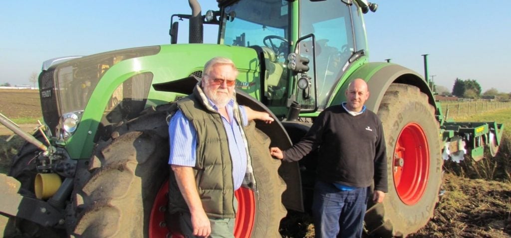 Two men standing in front of a Fendt tractor on a field