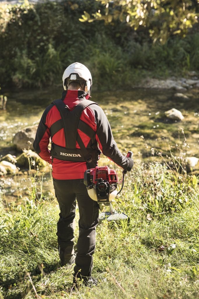 Honda Umk435 Xeet 47Cc Bike Handle Petrol Brushcutter in action with a man in safety gear by a stream