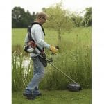 A man in safety glasses and gloves cuts long grass using a Honda Loop Handle Backpack Petrol Brushcutter.