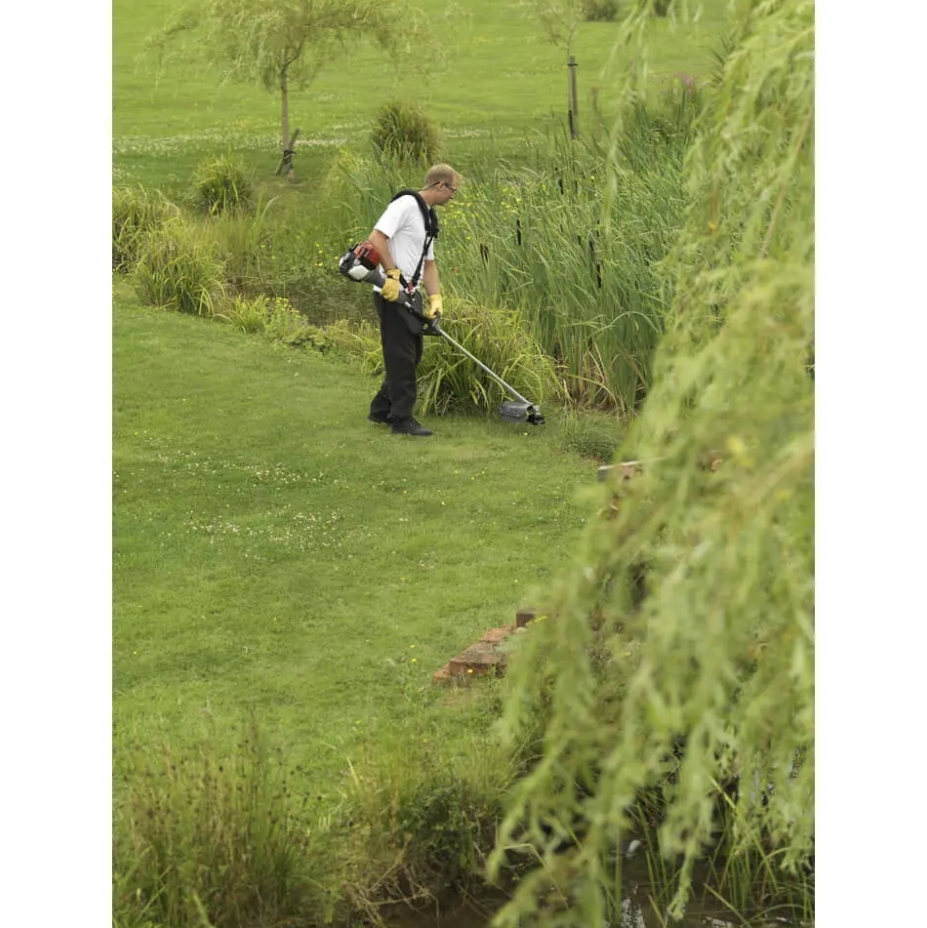 A man using a Honda UMR435 LE 35cc Loop Handle Backpack Petrol Brushcutter