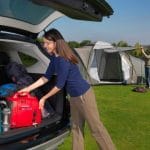 Woman removing a Honda EU10i Inverter Generator out of the back of car for camping in a field